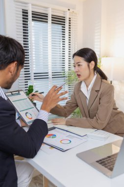 İş arkadaşları renkli çizelge ve raporları gözden geçirmek için finansal bir toplantıdalar. Etkili sonuçlar elde etmek için fikir alışverişinde bulunur, notlar alır ve stratejileri analiz ederler..