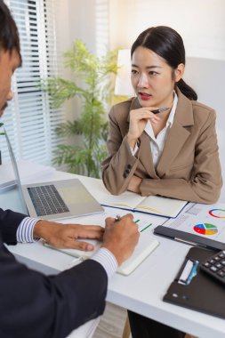 İş arkadaşları renkli çizelge ve raporları gözden geçirmek için finansal bir toplantıdalar. Etkili sonuçlar elde etmek için fikir alışverişinde bulunur, notlar alır ve stratejileri analiz ederler..