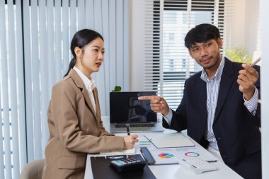 İş arkadaşları ortak bir tartışma içindeler, finansal tabloları ve raporları analiz ediyorlar. Fikir alışverişinde bulunurlar, stratejileri gözden geçirirler ve gelecekteki hedefleri planlarlar..