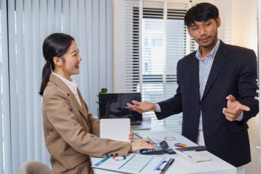 İş arkadaşları ortak bir tartışma içindeler, finansal tabloları ve raporları analiz ediyorlar. Fikir alışverişinde bulunurlar, stratejileri gözden geçirirler ve gelecekteki hedefleri planlarlar..