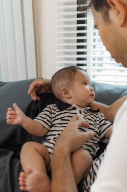 Bebeğini kucağında tutan bir babanın şefkatli anı. Bebek merakla ve güvenle yukarı bakıyor. Sıcak etkileşim aile sevgisini, yakınlaşmayı ve ebeveyn bakımını yansıtır..