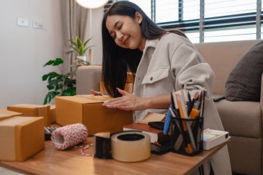 Tüm müşterilere göndermek için paket hazırlıyor. Bu girişimcinin küçük bir işletmesi var. Sme, internetten ürün satıyor.