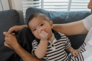 Bebeğini kucağında tutan bir babanın şefkatli anı. Bebek merakla ve güvenle yukarı bakıyor. Sıcak etkileşim aile sevgisini, yakınlaşmayı ve ebeveyn bakımını yansıtır..