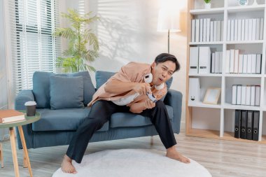 Neşeli bir genç adam evinde bir kanepede oturuyor, elinde bir oyun kumandası tutuyor ve neşe ve heyecanla video oyunları oynuyor, kahkaha ve zaferi ifade ediyor, aynı zamanda oyuna dalmış..