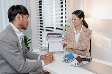 İki iş adamı emlak yatırımını tartışıyor, emlak sözleşmeleri imzalıyor ve ev modellerini gözden geçiriyor, konut satışlarını, finansmanı ve başarılı anlaşmaları sembolize ediyor.