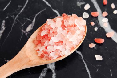 Himalaya pembe tuzu siyah mermer arka planda tahta kaşıkta.