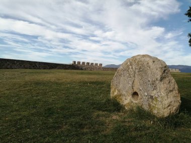 Güneşli bir günde çimlerin üzerinde eski güzel bir taş