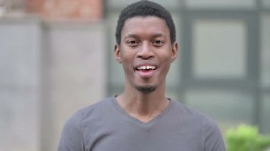 Kamerayı gösteren neşeli genç Afrikalı adamın portresi. 