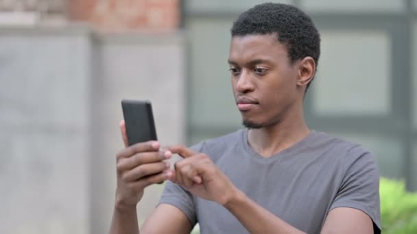 Portrett av spent ung afrikansk mann som feirer på Smartphone – stockvideo