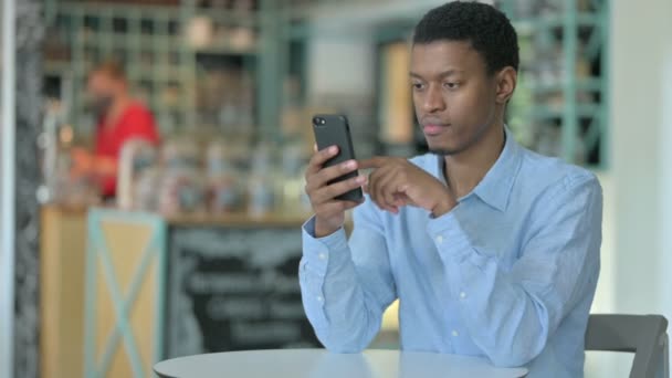 Ung afrikansk man använder Smartphone i Café — Stockvideo