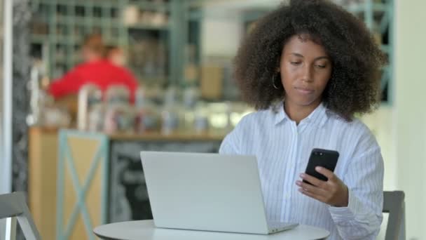 在咖啡店使用智能手机和笔记本电脑的非洲女商人 — 图库视频影像