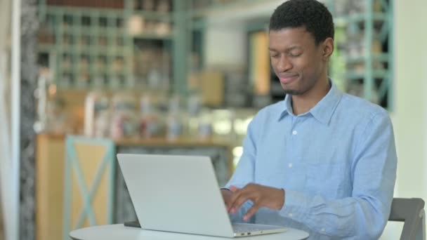 Mladý Afričan s notebookem s bolestí hlavy v kavárně — Stock video