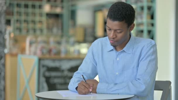 Focused Young African Man fare scartoffie in Cafe, Scrivere — Video Stock