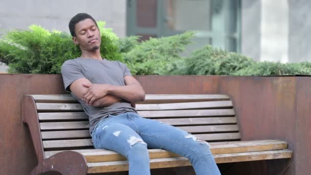 Cansado joven africano hombre takin siesta en banco al aire libre — Vídeos de Stock