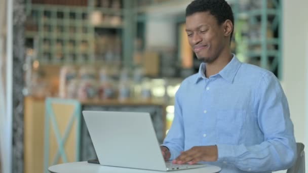 有背痛的非洲年轻人在咖啡店用笔记本电脑 — 图库视频影像