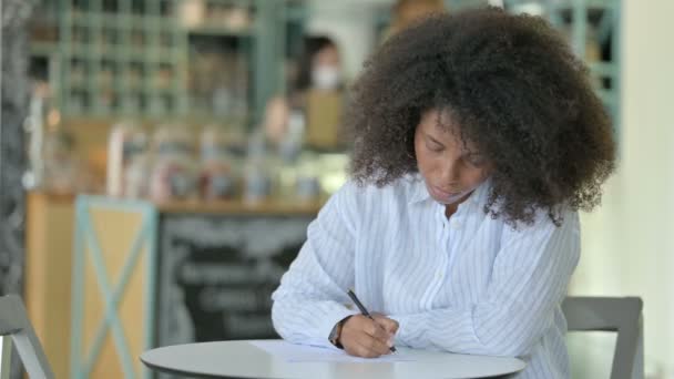 Schöne junge afrikanische Geschäftsfrau erledigt Papierkram im Cafe — Stockvideo