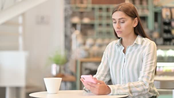 Fröhliche junge Latino-Frau spricht im Café mit Smartphone — Stockvideo