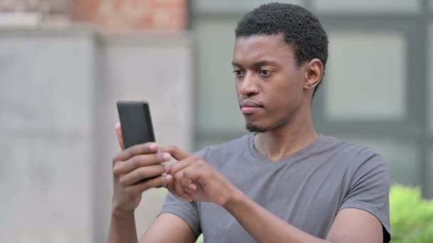 Porträtt av Upprörd ung afrikansk man med förlust på smartphone — Stockvideo