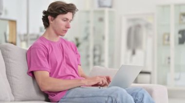 Evde dizüstü bilgisayar kullanan odaklı genç adam 