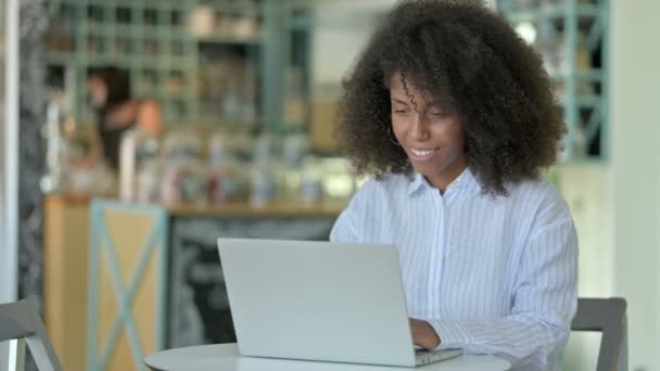 Aufgeregte afrikanische Geschäftsfrau feiert Erfolg auf Laptop im Café — Stockvideo