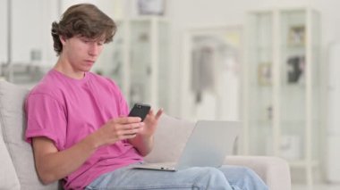 Evde akıllı telefon ve dizüstü bilgisayar kullanan sıradan bir genç. 