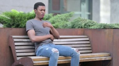 Hasta genç Afrikalı adam Bench 'te öksürüyor.