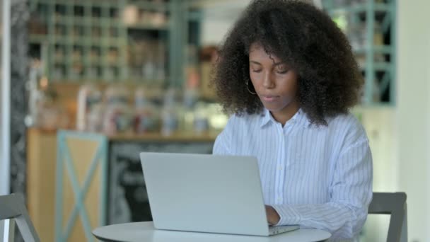 Mujer de negocios africana con computadora portátil mirando la cámara en el Café — Vídeos de Stock