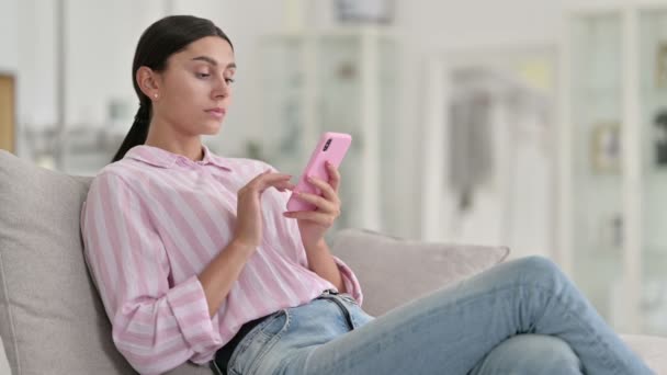 Entspannte junge Latino-Frau nutzt Smartphone zu Hause — Stockvideo