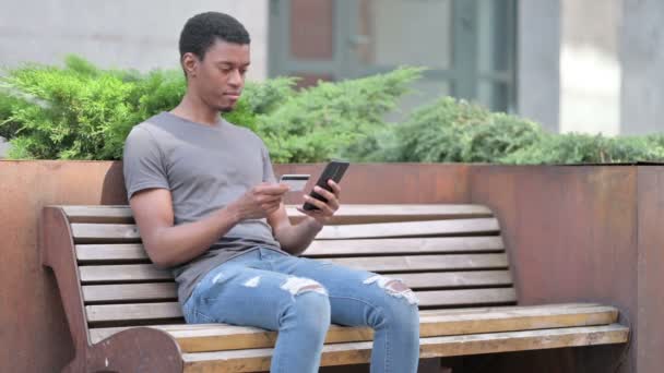 Ung afrikansk man att göra framgångsrika online-betalning på smartphone — Stockvideo