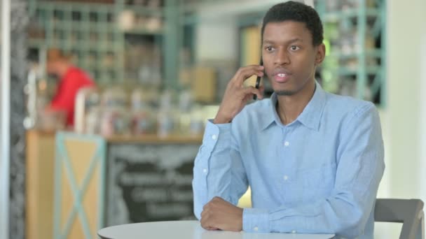 Afrikansk man pratar på smartphone i Café — Stockvideo