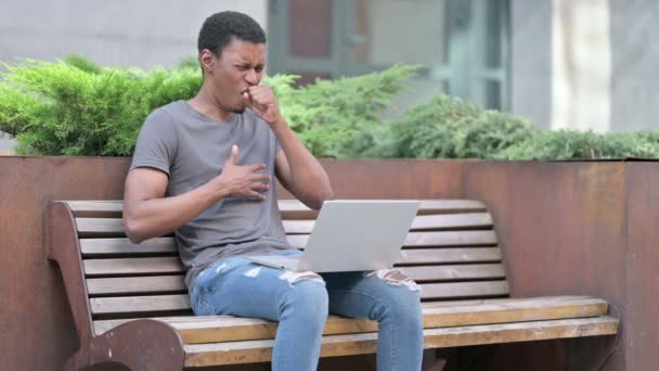 Bankta Öksüren Laptop kullanan hasta genç Afrikalı. — Stok video