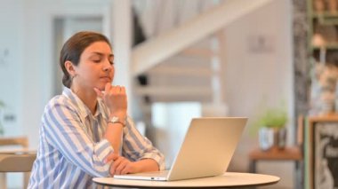 Kafe 'de laptopta düşünen ve çalışan düşünceli genç Hintli kadın. 