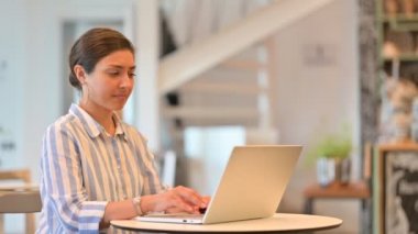 Kafede dizüstü bilgisayarlı hasta genç Hintli kadın öksürüyor. 