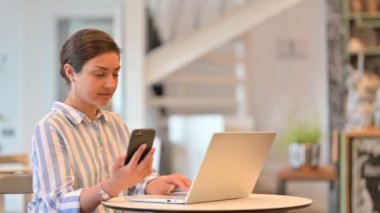 Cafe 'de akıllı telefon kullanan laptoplu çekici Hintli kadın. 