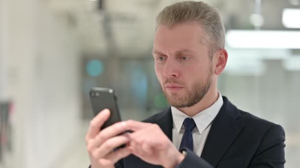 Retrato del joven empresario trastornado que tiene pérdida en el teléfono inteligente — Vídeo de stock