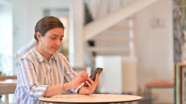 Kafe 'de akıllı telefon kullanan rahat genç Hintli kadın. 