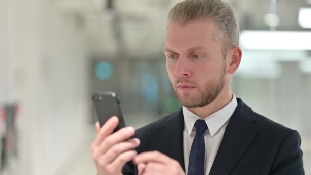 Porträt eines attraktiven Jungunternehmers mit Smartphone — Stockvideo