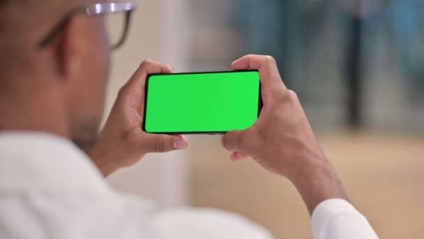 Vista posteriore del medico africano maschio che guarda Smartphone con schermo cromato — Video Stock