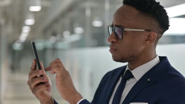 รูปภาพของนักธุรกิจชาวแอฟริกันที่ตอบสนองต่อการสูญเสียบนสมาร์ทโฟน — วีดีโอสต็อก