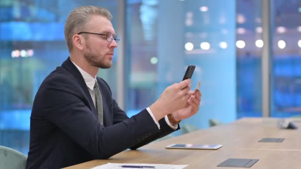 Бизнесмен, осуществляющий успешную онлайн-оплату на смартфоне в офисе — стоковое видео