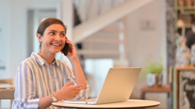 Laptoplu neşeli Hintli Kadın Kafe 'de Smartphone ile konuşuyor 