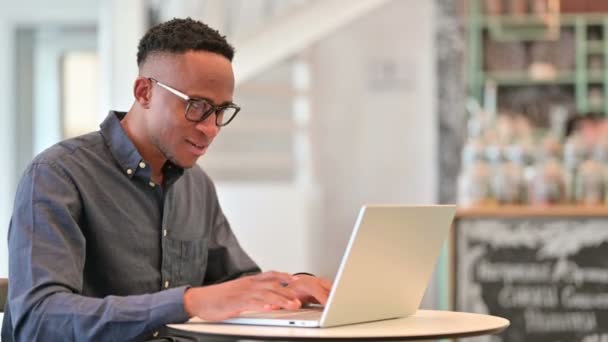 Emocionado hombre africano celebrando el éxito en el ordenador portátil en Café — Vídeos de Stock