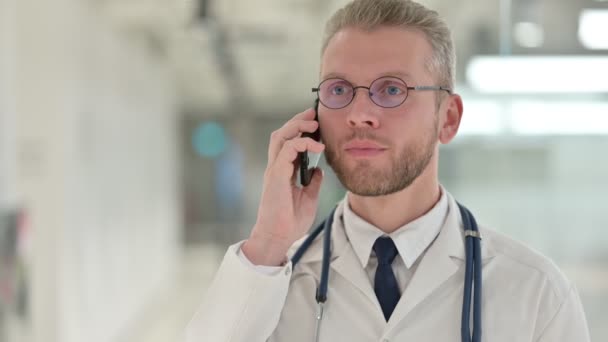 Porträt eines jungen männlichen Arztes, der mit dem Smartphone spricht — Stockvideo