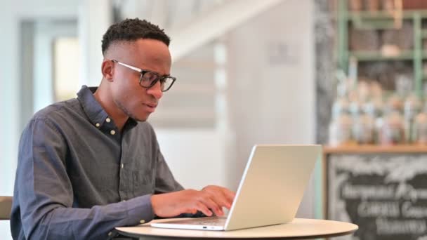 Zieke Afrikaanse man met laptop hoesten in Cafe — Stockvideo