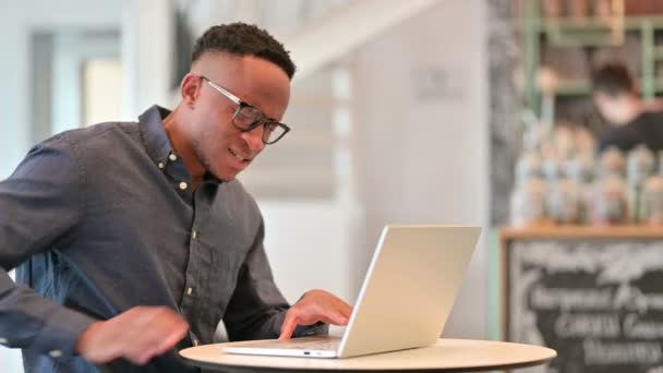 Stanco uomo africano con computer portatile con mal di schiena in Cafe — Video Stock