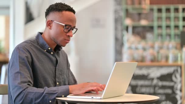 Focused africano uomo working su computer portatile in Cafe — Video Stock