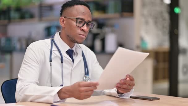 Professionele Afrikaanse Man Doctor Lezing Documenten in Office — Stockvideo