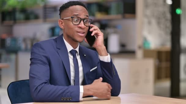 オフィスでスマートフォンで話す陽気なアフリカのビジネスマン — ストック動画