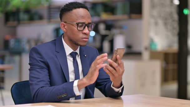 Ernstige Afrikaanse zakenman met behulp van Smartphone in Office — Stockvideo