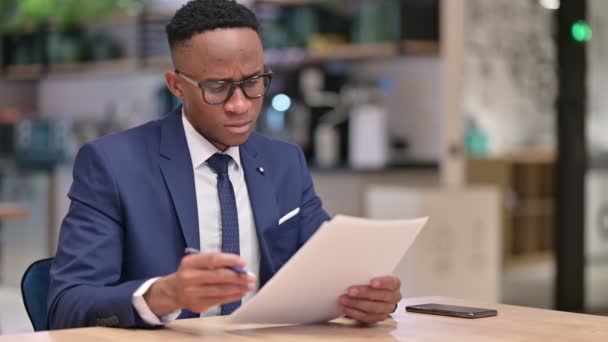 Zaměřený africký podnikatel Čtení dokumentů v kanceláři — Stock video